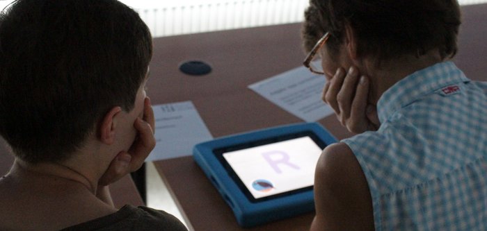 Zwei Frauen von hinten, die sich über ein iPad beugen