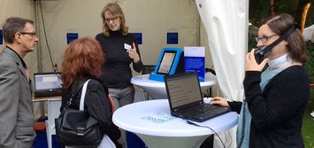 Susanne Böhmig am Stand der STIFTUNG barrierefrei kommunizieren! erklärt Besuchern unterstützende Technologien